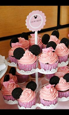 cupcakes with pink frosting and minnie mouse ears are on a cake stand