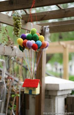 a house made out of legos is hanging from a trellis with balloons attached to it