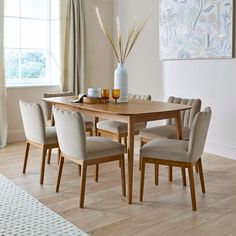 a dining room table with beige chairs around it