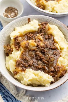 two bowls filled with mashed potatoes and meat