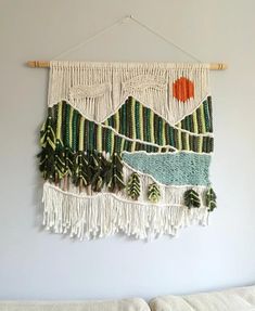 a tapestry hanging on the wall with trees and mountains in green, orange and white colors