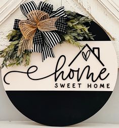 a home sign hanging on the side of a building with a bow attached to it