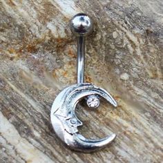 a silver belly ring with a crescent moon and diamond in the middle on top of a rock