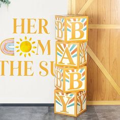 there is a wooden block that says her mom the sun next to a wall with letters on it