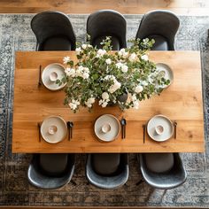 an overhead view of a dining room table with black chairs and white plates on it