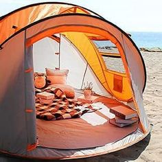 an orange and white tent sitting on top of a sandy beach