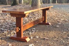 a wooden bench sitting in the middle of a forest with leaves on the ground around it