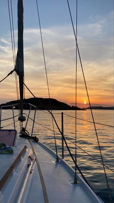 the sun is setting on a sailboat in the water