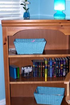 a book shelf with books and baskets on it