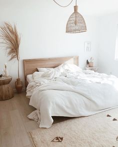 a bedroom with white linens and wooden furniture, including a bed that has been made