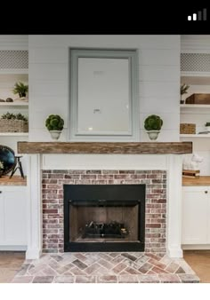 a fire place in a living room with white cabinets and shelves on the wall behind it