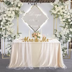 a table with flowers and a sign that says mr and mrs on it in front of a backdrop