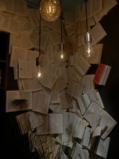 a bunch of books that are hanging from the ceiling with light bulbs on top of them