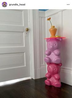 a pink and purple vase with a flower in it sitting on top of a wooden floor