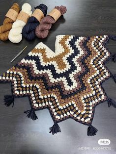 a crocheted blanket and two skeins of yarn sitting on a table