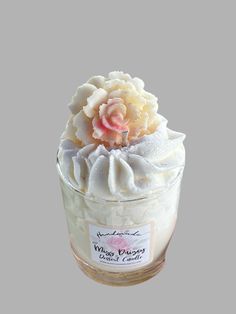 a glass jar filled with whipped cream and a pink flower on top of the jar