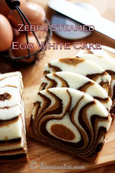 zebra - themed egg white cake on a wooden cutting board with eggs in the background