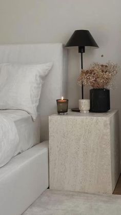 a bedroom with a white bed and a black lamp on top of the night stand