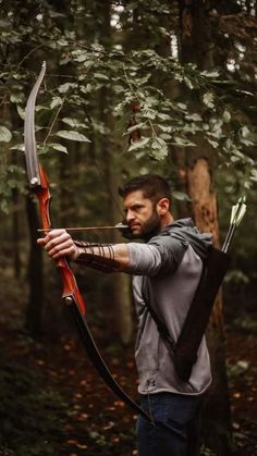 a man with a bow and arrow in the woods