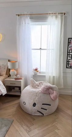 a bedroom with a hello kitty bean bag chair in the corner and a cat pillow on the floor