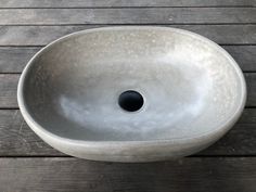 a white bowl sitting on top of a wooden table next to a black hole in the center