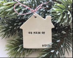 a house ornament hanging from a christmas tree with the words,'85 main street'written on it