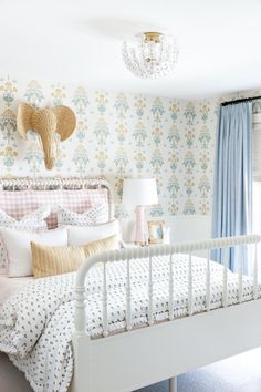 a white bed sitting in a bedroom next to a window with blue and yellow curtains