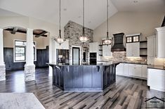 a large kitchen with an island in the middle and two pendant lights hanging from the ceiling