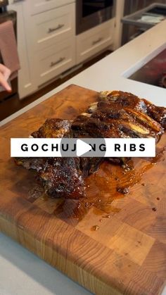 a wooden cutting board topped with ribs on top of a kitchen counter