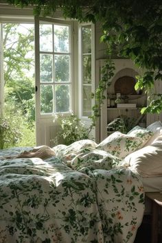 an unmade bed sitting in front of a window next to a plant covered wall