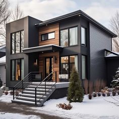 a modern house in the winter with snow on the ground and stairs leading up to it