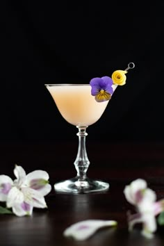 an alcoholic drink with flowers on the rim