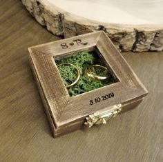 two wedding rings in a wooden box with moss