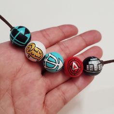 a hand holding five different colored beads