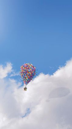 a bunch of balloons floating in the air on a cloud filled blue sky with white clouds