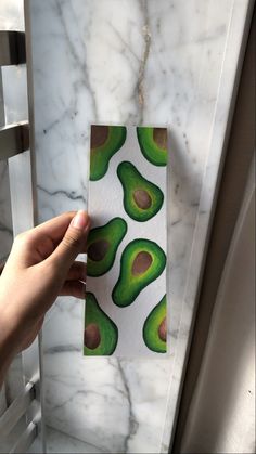 an avocado sticker is being held up against a marble wall with green and brown spots