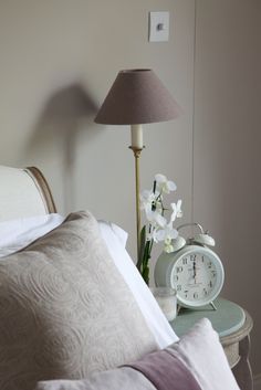 an image of a bedroom setting with flowers on the nightstand and lamp next to it