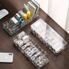 two clear plastic containers filled with electronics on top of a wooden table next to an iphone