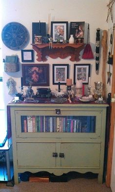 an old dresser with books and pictures on the wall