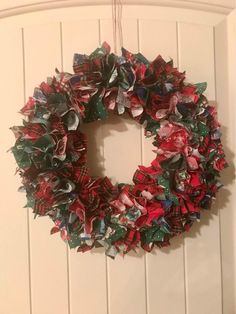 a christmas wreath hanging on the door with red and green paper flowers attached to it