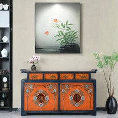 an orange and blue cabinet with flowers on it in front of a black bookcase