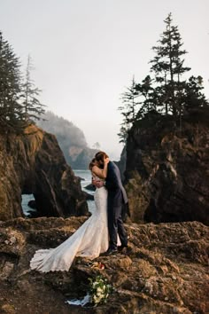 a bride and groom kissing on the rocks by the water at their wedding in oregon