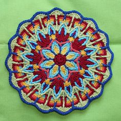 a colorful crocheted doily on a green surface