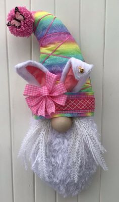 a colorful gnome head hanging on the side of a white door with a pink bow