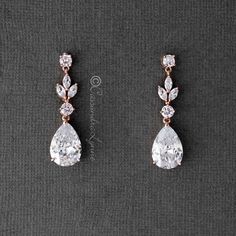 two pairs of earrings with white stones and diamonds on the bottom, one has a tear shaped