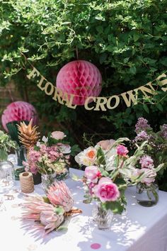 a table topped with vases filled with flowers next to a sign that says floral crowns