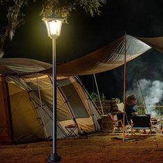 a person sitting at a table in front of a tent with a laptop on it