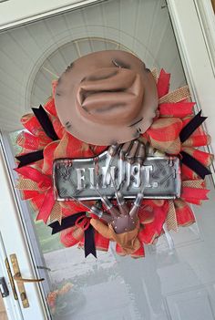 a welcome sign hanging on the front door to a house that has been decorated with red, orange and black ribbons