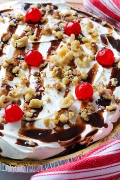 a cake with white frosting, cherries and nuts on top in a pan