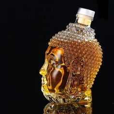 a glass bottle with an image of buddha head on it's side, in front of a black background